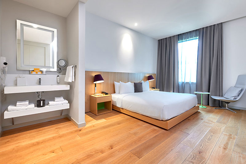 ADA Accessible King bedroom at Hotel SoJo designed with Eastern Asian aesthetic, minimal furtinure, bright lights and wood floors.