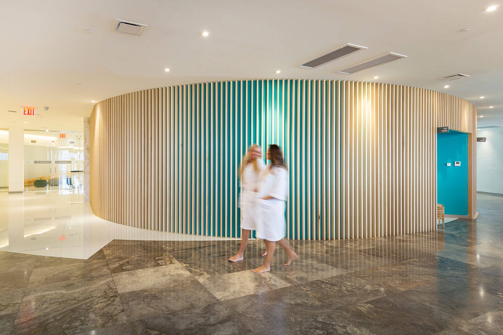 Two blurred women in bath robes walking through a building