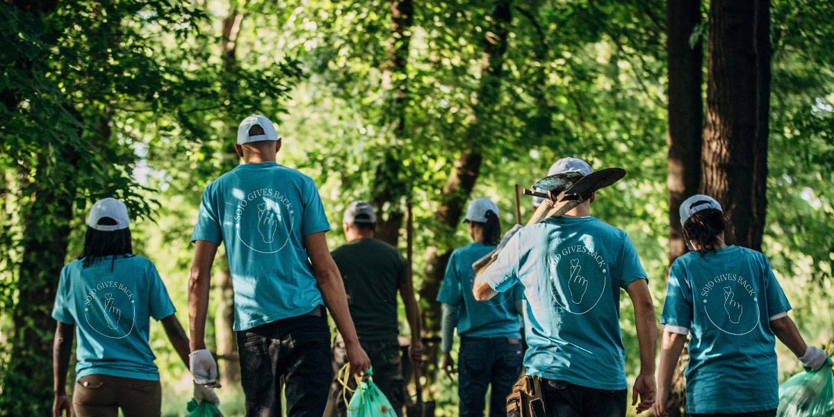 People walking in woods wearing SoJo gives back tshirts