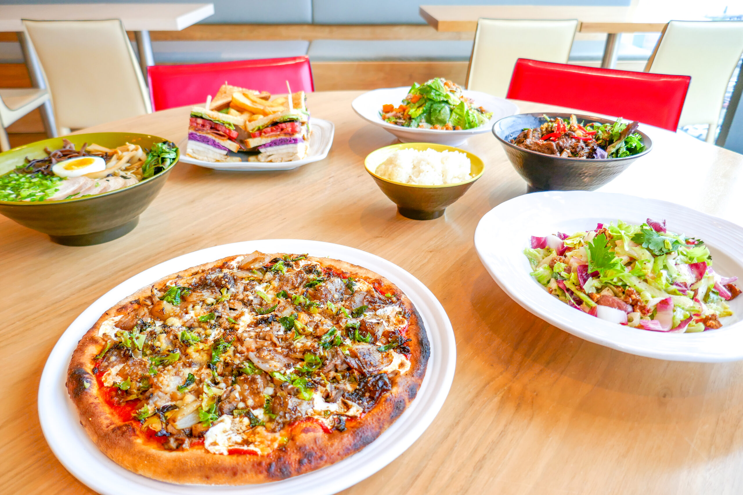 Close up of the Sausage Pizza and Autumn Chopped Salad with other food dishes in the background