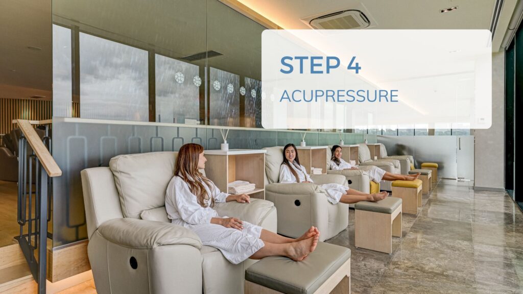 Three girls in spa robes in plush leather chairs with their feet up. Overlaying text says "Step 4, Acupressure"