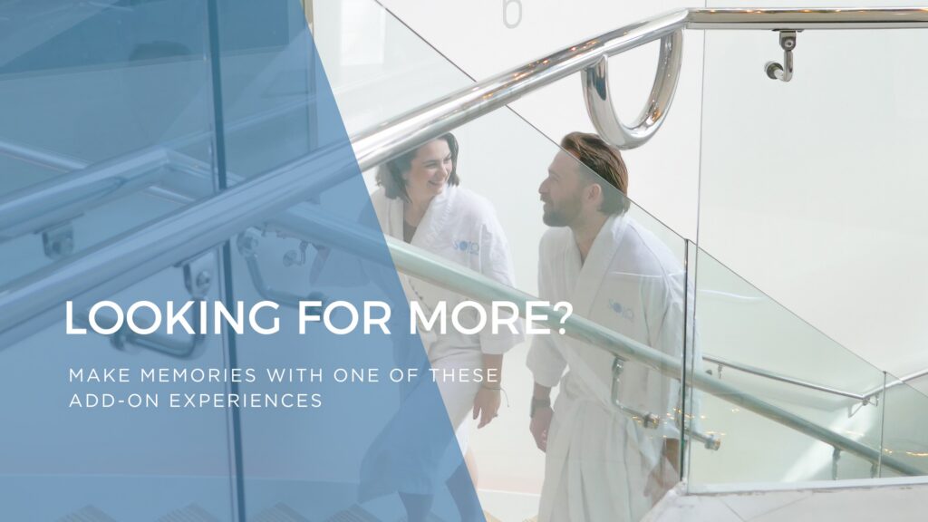 A couple walking up the stairs at a spa, with white walls and silver railings. Couple is wearing spa robes. Overlaying text says "Looking for More?"