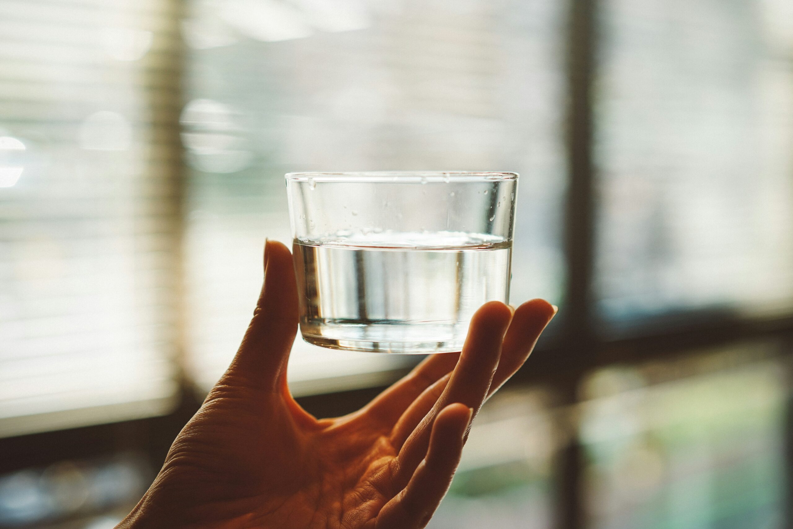 A hand holding a short glass of water